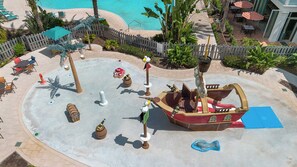 Un espace de jeux sur le thème des pirates, avec un bateau, des tonneaux et un coffre au trésor.