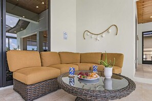 Ein modulares Sofa mit einem Glastisch davor, ein Schild mit Poolregeln und ein dekoratives Wandbild.