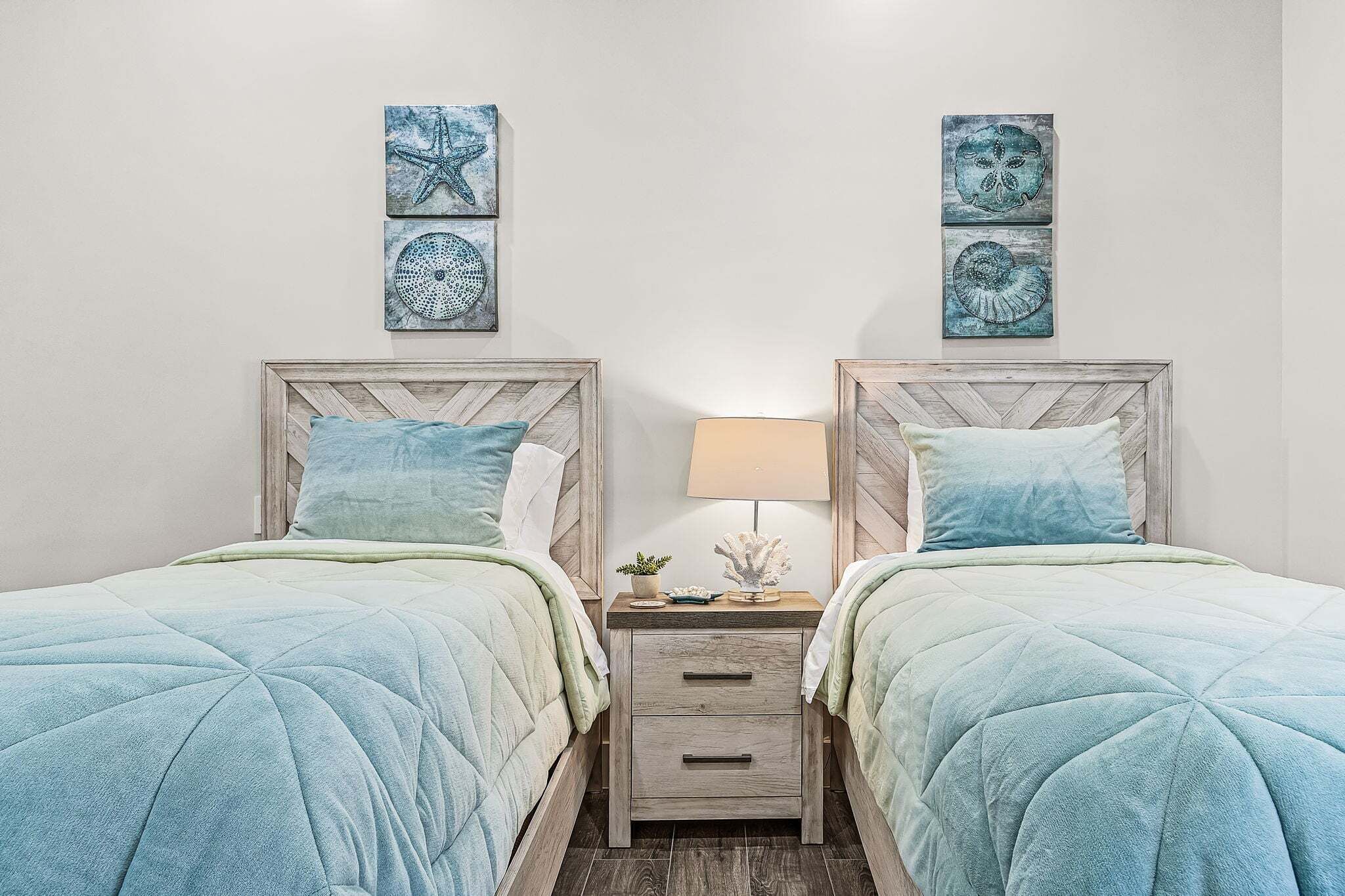 A bedroom with two beds, a nightstand, and wall art.