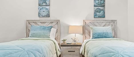 A bedroom with two beds, a nightstand, and wall art.