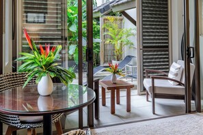 Ein verglaster Patio-Bereich mit Esstisch, Stühlen und einem kleinen Tisch mit Blumenvase.