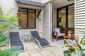 Eine Terrassenfläche mit zwei Liegestühlen, einem kleinen Tisch und einem Blumentopf.