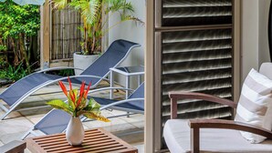 A patio area with a wooden table, a chair, a potted plant, and a sliding glass door. - SeaEden @ The Temple Studio Spa Apartment (Craiglie)