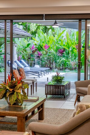 A modern indoor space with a glass door leading to a tropical garden. - SeaEden @ The Temple 3 Bedroom with Private Pool (Craiglie)