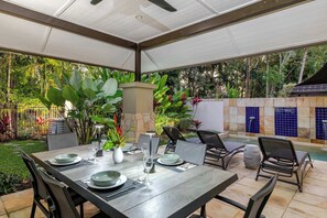 An outdoor dining area with a table set for two, surrounded by chairs, and a pool in the background. - SeaEden @ The Temple 2 Bedroom with Private Pool (Craiglie)