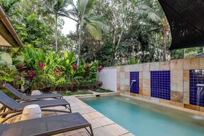 A pool area with lounge chairs, a tiled wall, and lush tropical plants. - SeaEden @ The Temple 2 Bedroom with Private Pool (Craiglie)
