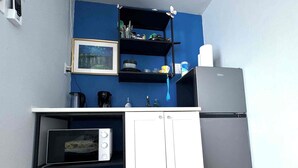 A compact kitchenette with a microwave, a coffee maker, and a refrigerator.