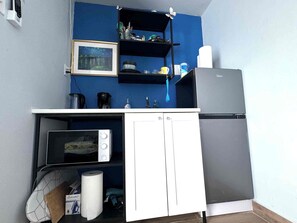 A compact kitchenette with a microwave, a coffee maker, and a refrigerator.