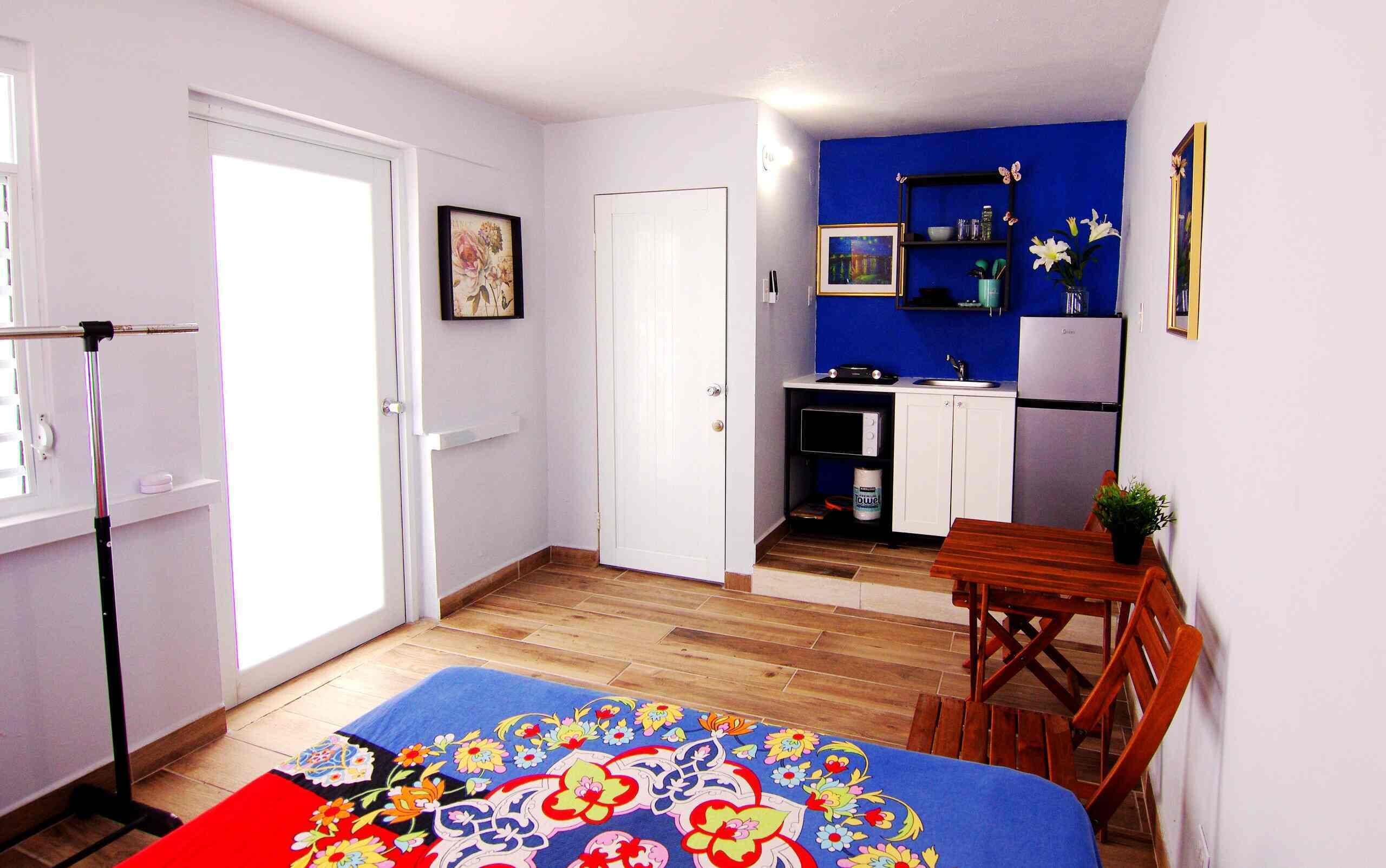 A compact living space with a kitchenette, a dining area, and a bedroom.