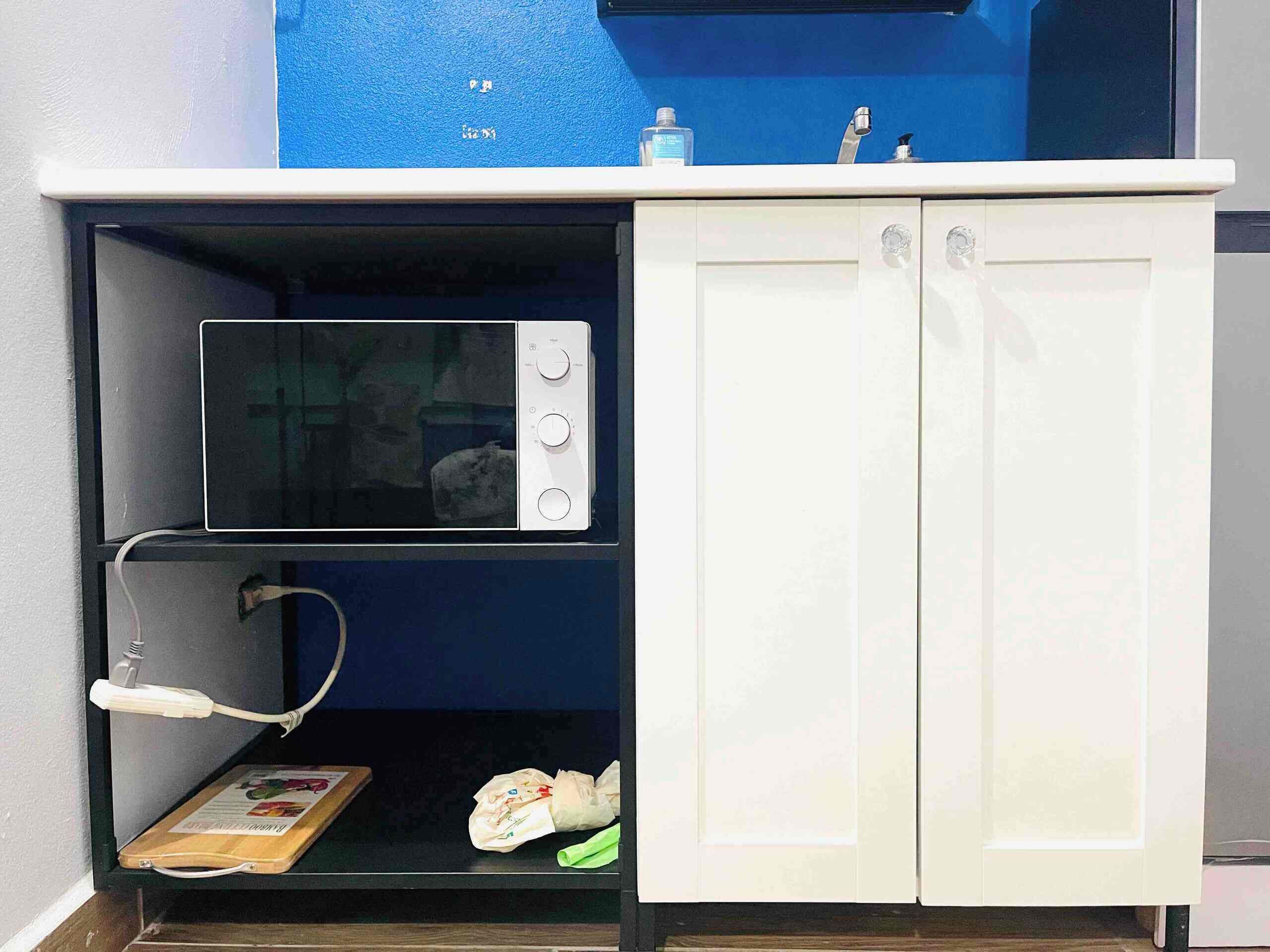 A kitchen with a microwave, a sink, and cabinets.