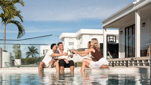 A group of people sitting by a swimming pool with a modern house in the background. - The Sanctuary by Aryve (Mermaid Waters)