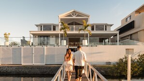 A modern two-story house with a covered porch, a balcony, and a view of the water. - The Sanctuary by Aryve (Mermaid Waters)