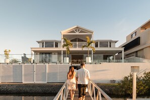 A modern two-story house with a covered porch, a balcony, and a view of the water. - The Sanctuary by Aryve (Mermaid Waters)
