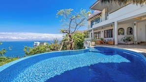 A pool with a clear view of the sea, a tree, and a building with outdoor seating. - Stunning 5BR Oceanview Villa in Conchas Chinas (Puerto Vallarta)