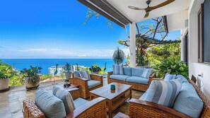 A sunlit outdoor seating area with wicker furniture, a ceiling fan, and a view of the ocean. - Stunning 5BR Oceanview Villa in Conchas Chinas (Puerto Vallarta)