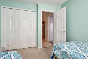 A bedroom with two beds, a closet, and a door leading to a hallway. - Best Value Near Disney! Private Pool, BBQ, Fenced Yard & Room for 8 (Kissimmee)