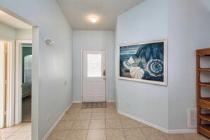 A hallway with a door, a patterned rug, and a framed painting on the wall. - Best Value Near Disney! Private Pool, BBQ, Fenced Yard & Room for 8 (Kissimmee)