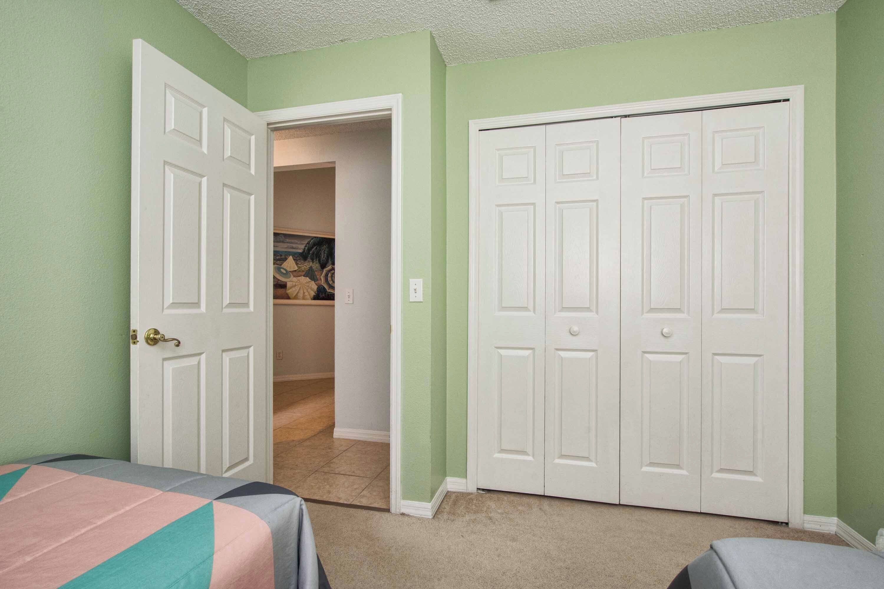 A bedroom with two beds, a closet, and a door leading to a bathroom.
