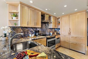 A modern kitchen with granite countertops, stainless steel appliances, wooden cabinets, and a built-in oven. - Whaler 1261 Beautiful Studio Ocean View - Special introductory rates (Lahaina)