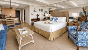 A modern hotel room with a large bed, a sitting area with a sofa and armchair, a small desk, and a kitchenette. - Whaler 1261 Beautiful Studio Ocean View - Special introductory rates (Lahaina)