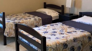 Ein Schlafzimmer mit zwei Einzelbetten, einem Deckenventilator und einem Nachttisch mit Lampe.