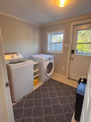 A laundry room with a washing machine, dryer, and a window.