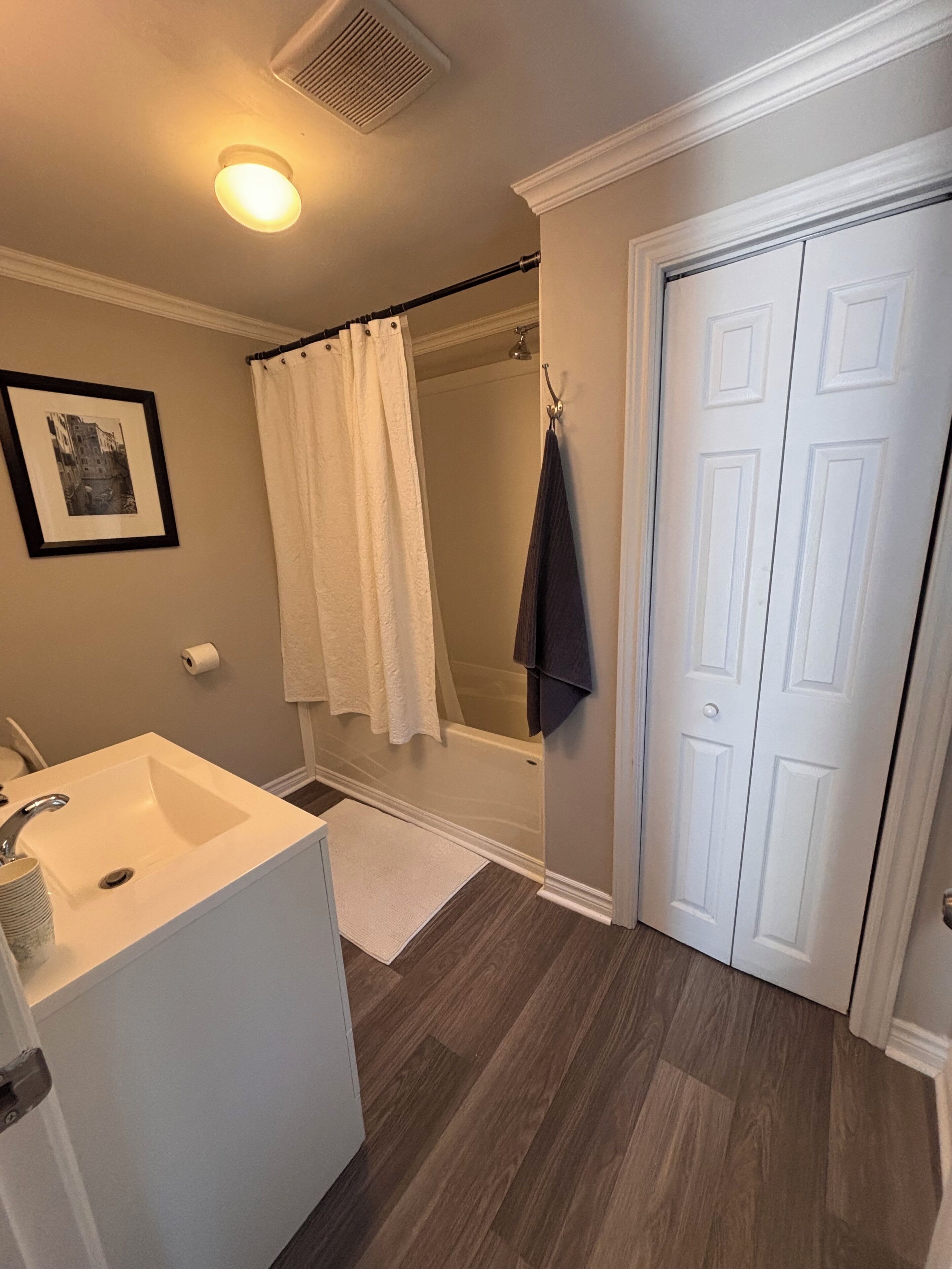 Een badkamer met een wit wastafelmeubel, een douche en een deur.