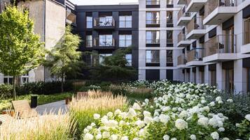 Un moderno edificio de apartamentos con balcones y un jardín lleno de flores blancas.