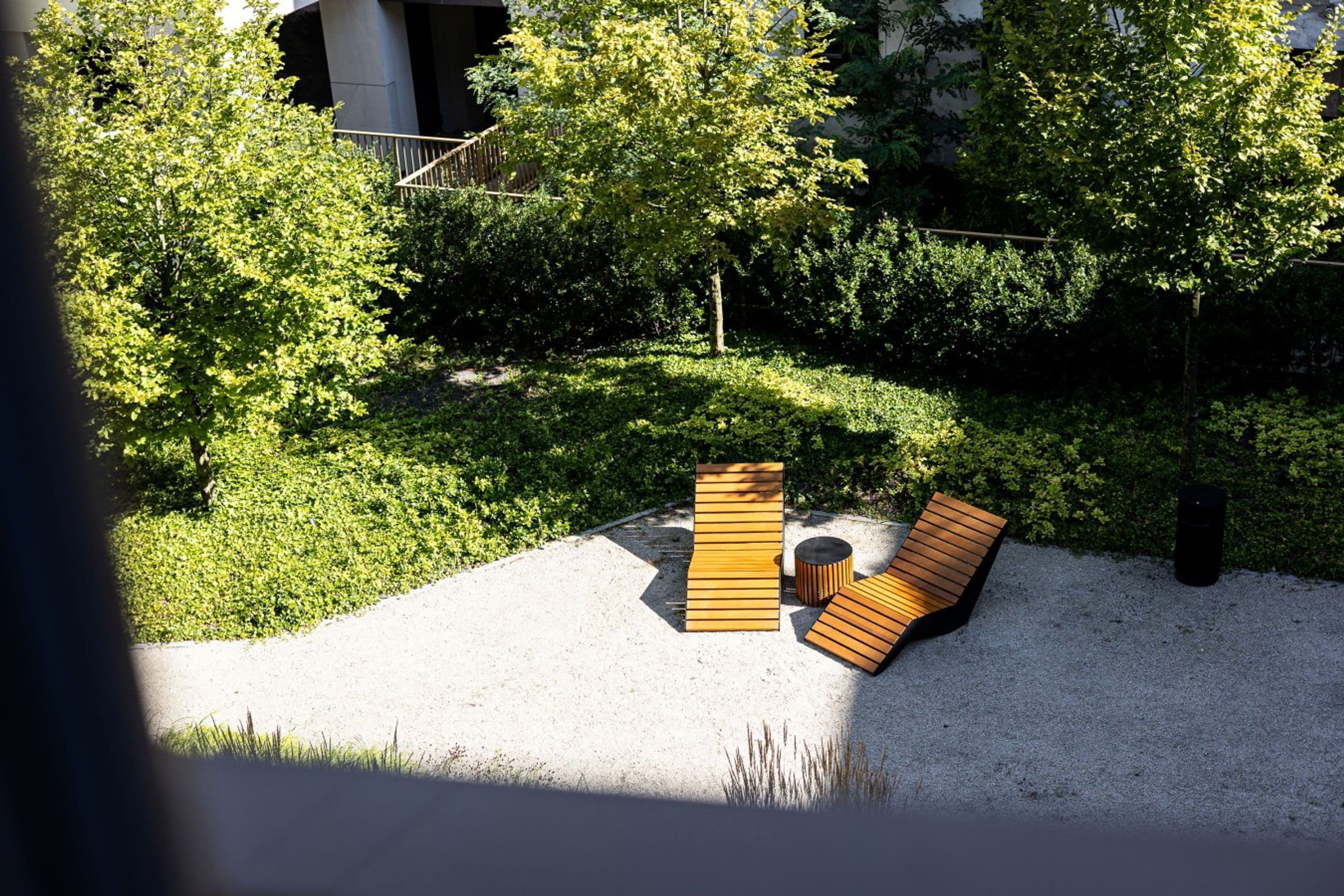 Un espacio al aire libre moderno con bancos de madera y una pequeña mesa redonda.