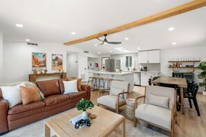 Ein modernes Wohnzimmer mit einem braunen Ledersofa, einem Couchtisch und einem Essbereich mit einem Holztisch und Stühlen.