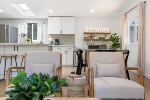 Ein modernes Wohnzimmer mit zwei Sesseln, einem Couchtisch und einem Bücherregal mit Dekoration.