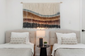 Ein Hotelzimmer mit zwei Betten, einem kleinen Tisch mit einer Lampe und einem dekorativen Wandbild.