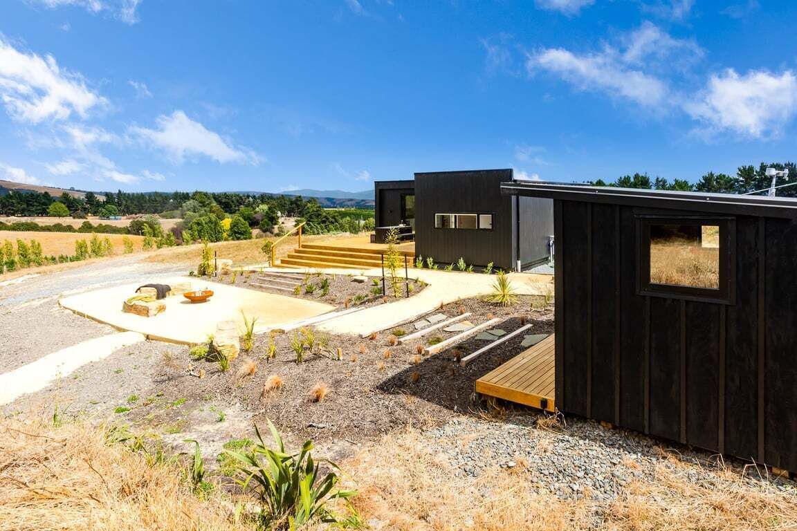 Et moderne hus med en belagt indkørsel, udendørs siddeplads og en træterrasse.