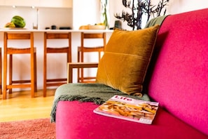 A living room with a red sofa, a mustard-colored pillow, and a magazine on the armrest. - Long Bush Nook - Marinborough (Greytown)