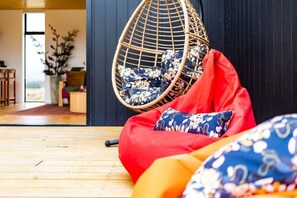 A room with a hanging chair, a red bean bag, and a wooden floor.