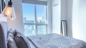 Una camera da letto moderna con un'ampia finestra, un letto con biancheria a motivi e un lampadario fissato alla parete.