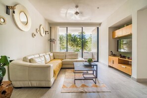 Ein modernes Wohnzimmer mit einer Couch, einem Couchtisch und einem Fernseher auf einer Holzkommode.