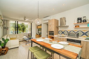 Eine moderne Küche mit Essbereich, darunter ein Holztisch für vier Personen, ein eingebauter Backofen und eine Mikrowelle.