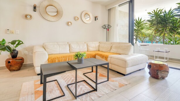 En moderne stue med en hvid sofa, et sofabord og dekorative vægspejle.