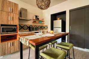 A modern kitchen with wooden cabinets, a microwave, a toaster, and a refrigerator. - 2 King Beds | Rooftop Pool | Walk to Beach & 5th Ave (Playa del Carmen)