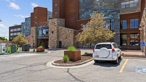 Un edificio moderno con facciate in mattoni e pietra, un'area di parcheggio con un SUV bianco e un cartello con la scritta 'NEWPARK'.