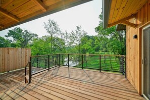 A wooden deck with a metal railing overlooking a river and trees. - Ramblewood Lodging 1 (Athens Township)