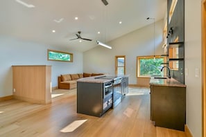 A modern kitchen with a central island, built-in ovens, and a ceiling fan. - Ramblewood Lodging 1 (Athens Township)