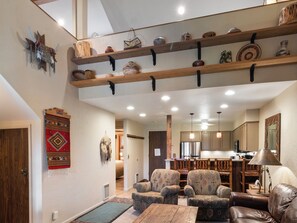 A spacious living area with a high ceiling, a kitchen in the background, and a dining area. - Snow Flower 124 | Ski-In/Ski-Out | Loft | Pools & Hot Tub (Park City)