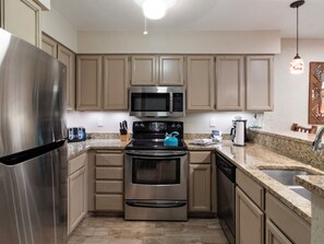 A kitchen with stainless steel appliances, beige cabinetry, granite countertops, and a built-in microwave. - Snow Flower 124 | Ski-In/Ski-Out | Loft | Pools & Hot Tub (Park City)