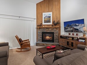 Ein Wohnzimmer mit Kamin, Wandfernseher und Bücherregal.