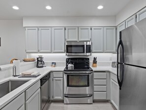 A modern kitchen with stainless steel appliances, white cabinetry, and a built-in oven. - Snow Flower 152 | Ski-In/Ski-Out | Loft | Mountain Views | Pool & Hot Tub (Park City)