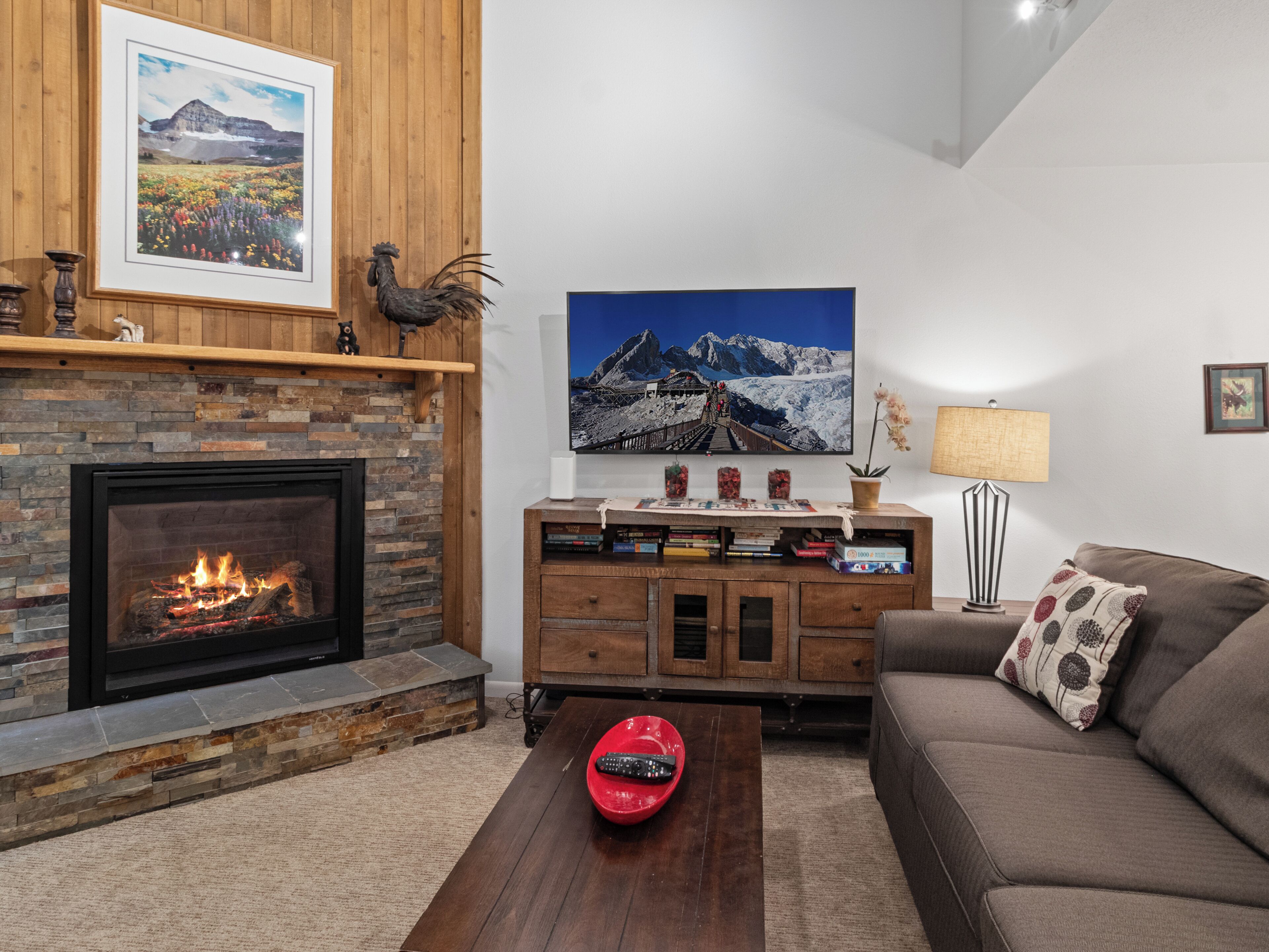 A living room with a fireplace, a mounted painting, a bookshelf, and a sofa.