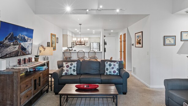 Uma sala de estar moderna com sofá, mesa de centro e área de jantar com cadeiras.