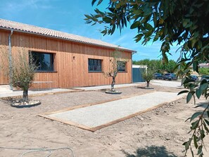Ein Holzhaus mit zwei Fenstern und einer Schotterauffahrt.